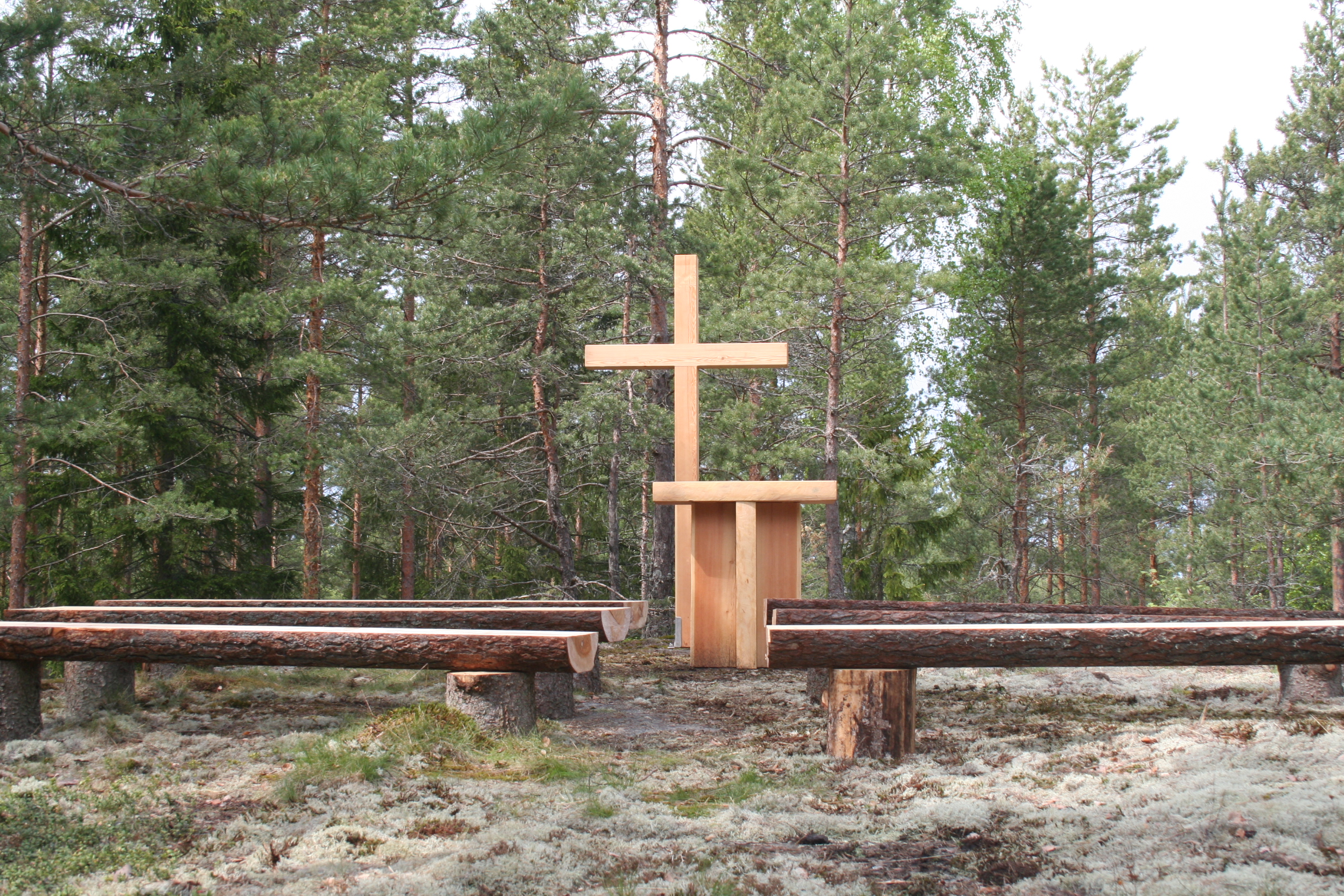 Metsäkirkko, jossa alttari, risti ja puupenkit